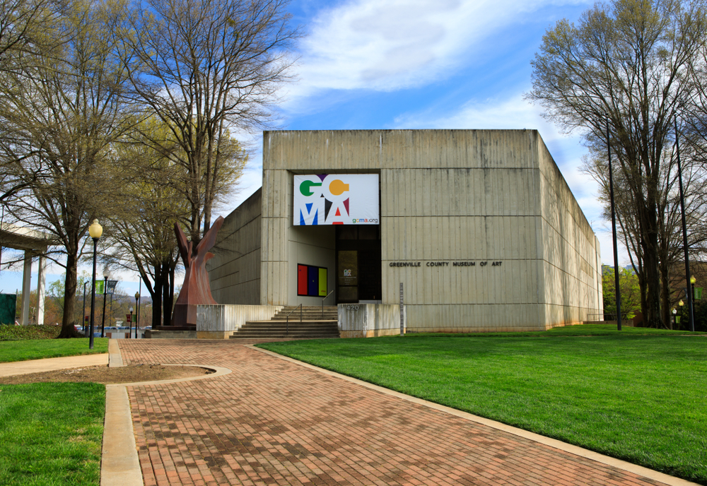 A concrete building surrounded by tall trees, green grass and paving, the Greenville County Museum of Art is one of the best things to do in Greenville