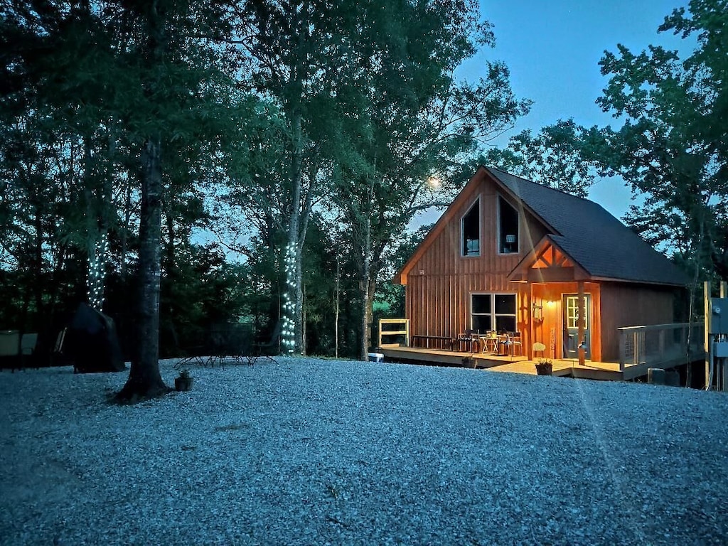 The light is fading in front of a wooden cabin surrounded by trees decorated with fairy lights. A light dusting of snow covers the foreground one of the best places for glamping in Arkansas