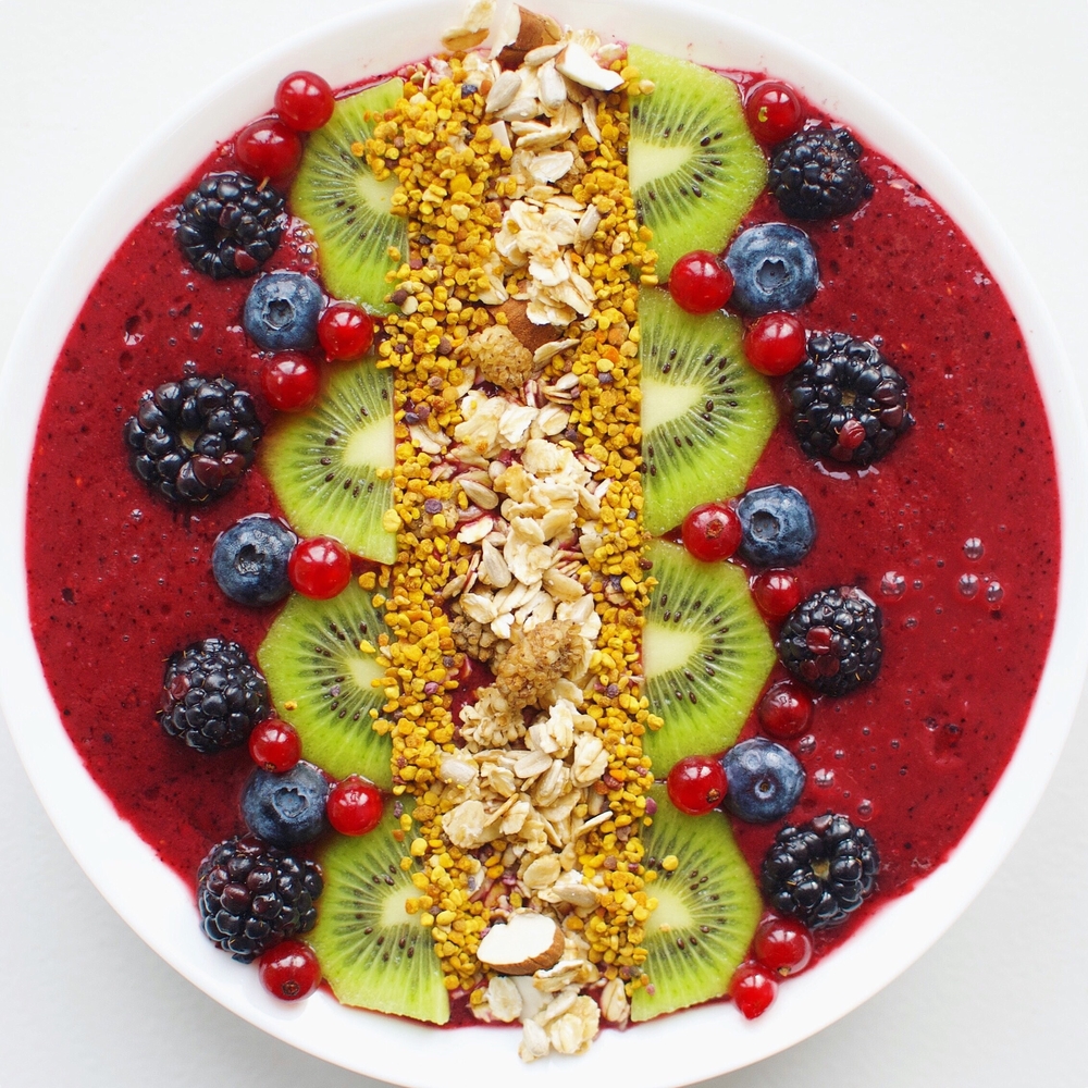 An açaí bowl with berries, kiwi, bee pollen and nuts