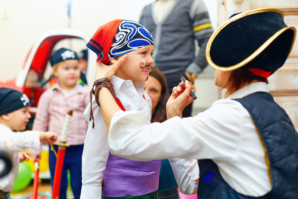 A child being given a fake mustache by an adult dressed like a pirate. The child, and ones behind them, is dressed like a pirate too. Its one of the best things to do in Hilton Head. 