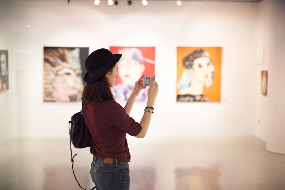 A woman in a gallery of contemporary art taking a picture. 