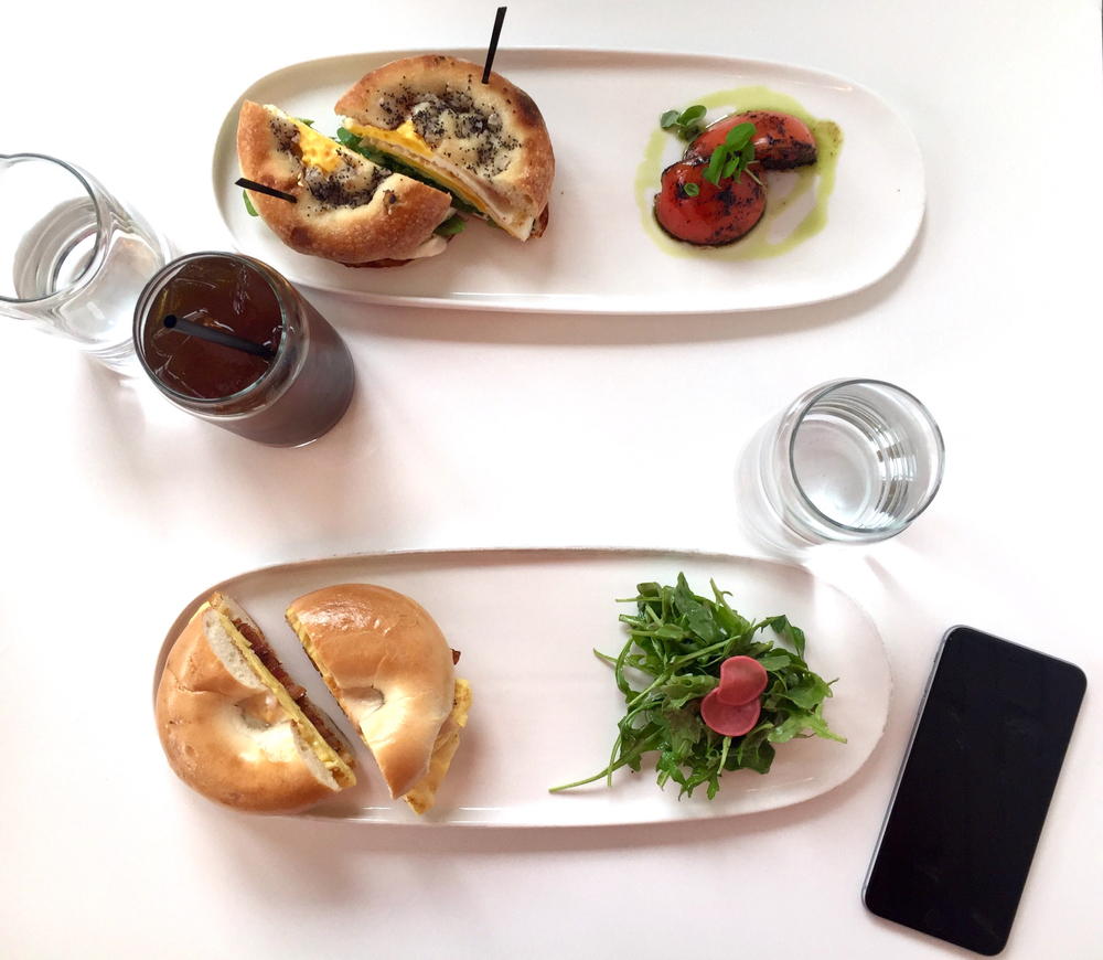 2 bagel breakfasts on a white plate with roasted tomatoes