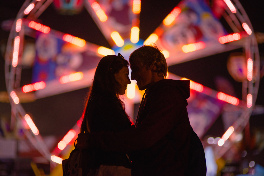 Photo of a couple in front of a ferris wheel.