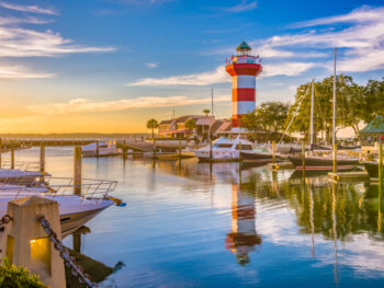 A scenic view of the marina with the white and red lighthouse, one of the best things to do in Hilton Head.