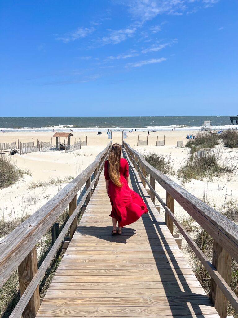 Women in a red dress walking along the broadwalk to the beach 