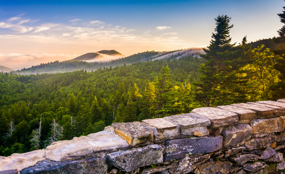 Sunset view from Devil's Courthouse with a stone fence in the foreground and cloudy mountains in the distance.