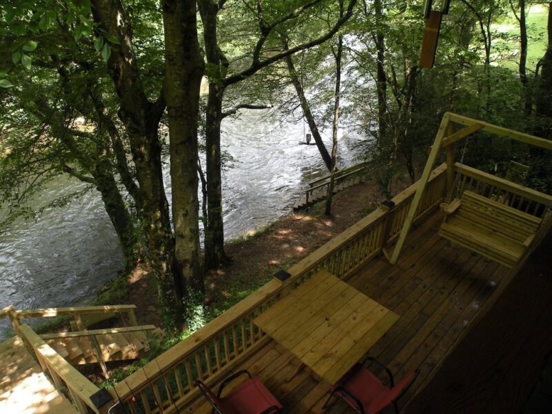 An overhead image looking down at a deck with wooden furniture, right beside a lake. This is one of the bets North Georgia cabin rentals.