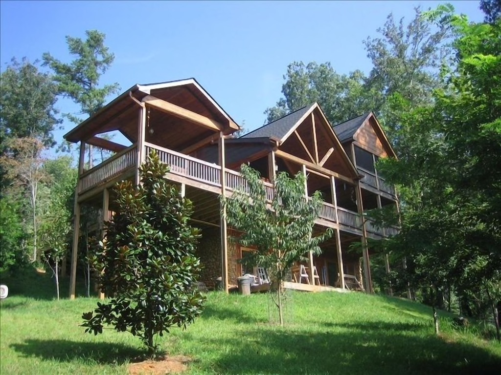 A large cabin with three peaked roof's and a green grassy hill. One of the best North Georgia cabins. 