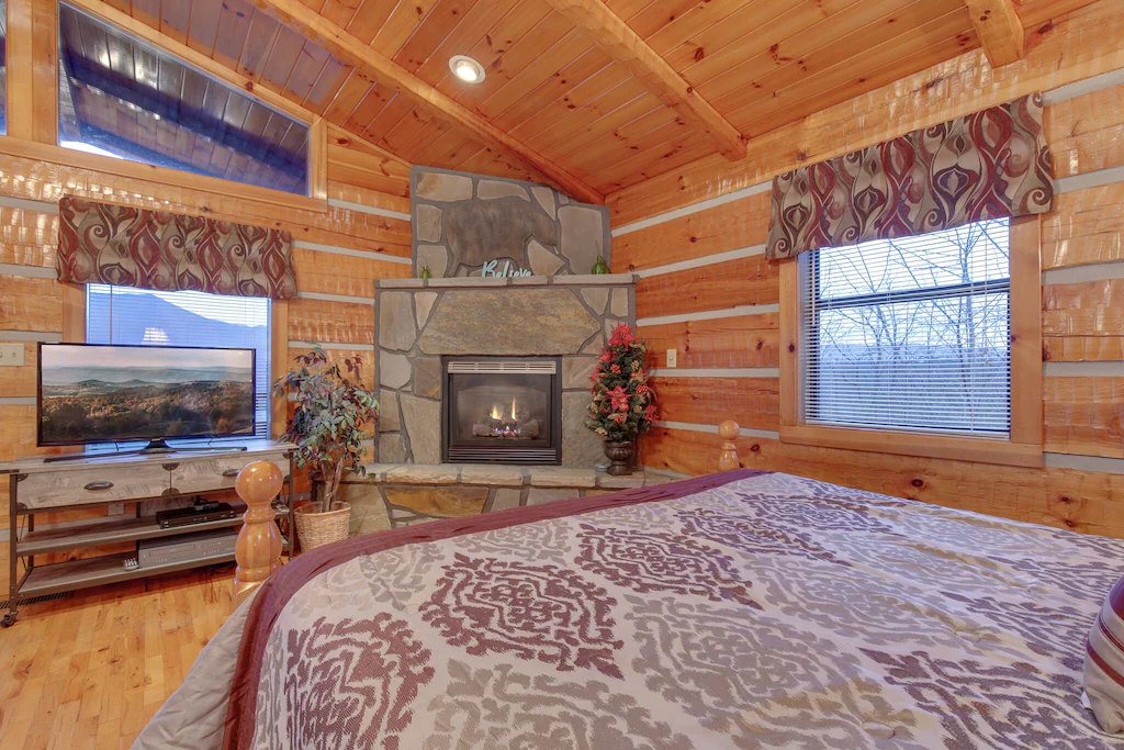 Cabin interior with a fireplace and bed. 