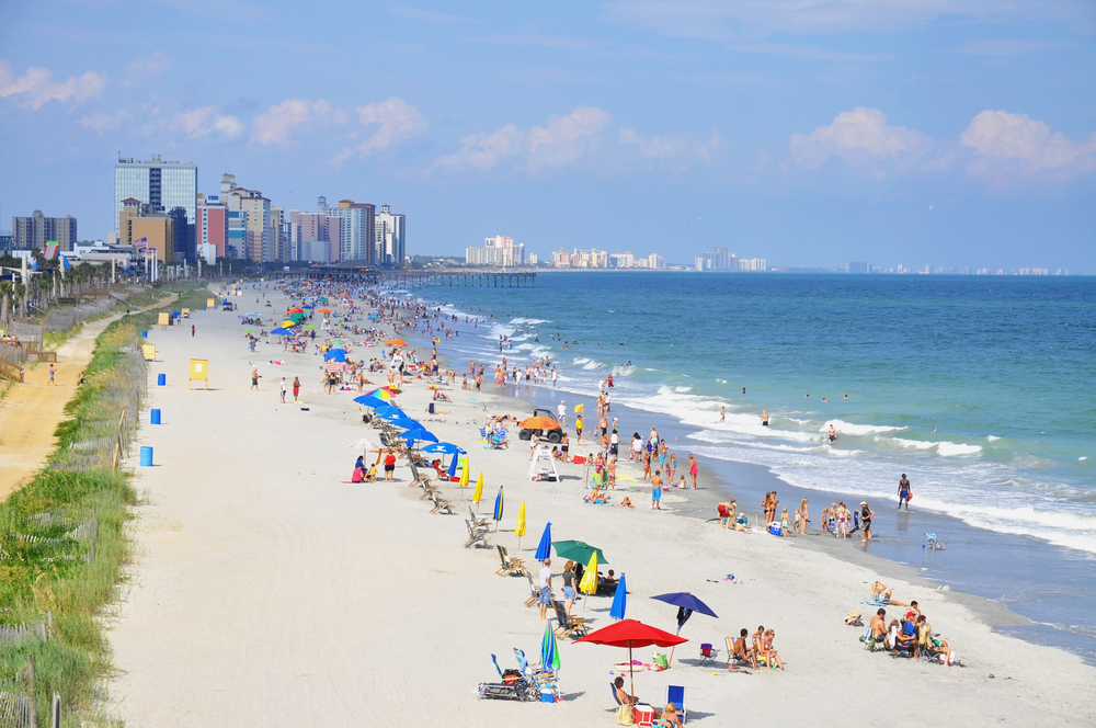 Myrtle beach is one of the most popular beach towns in South Carolina, as shown here with the crowds down the miles of shore line, the city in the background. 