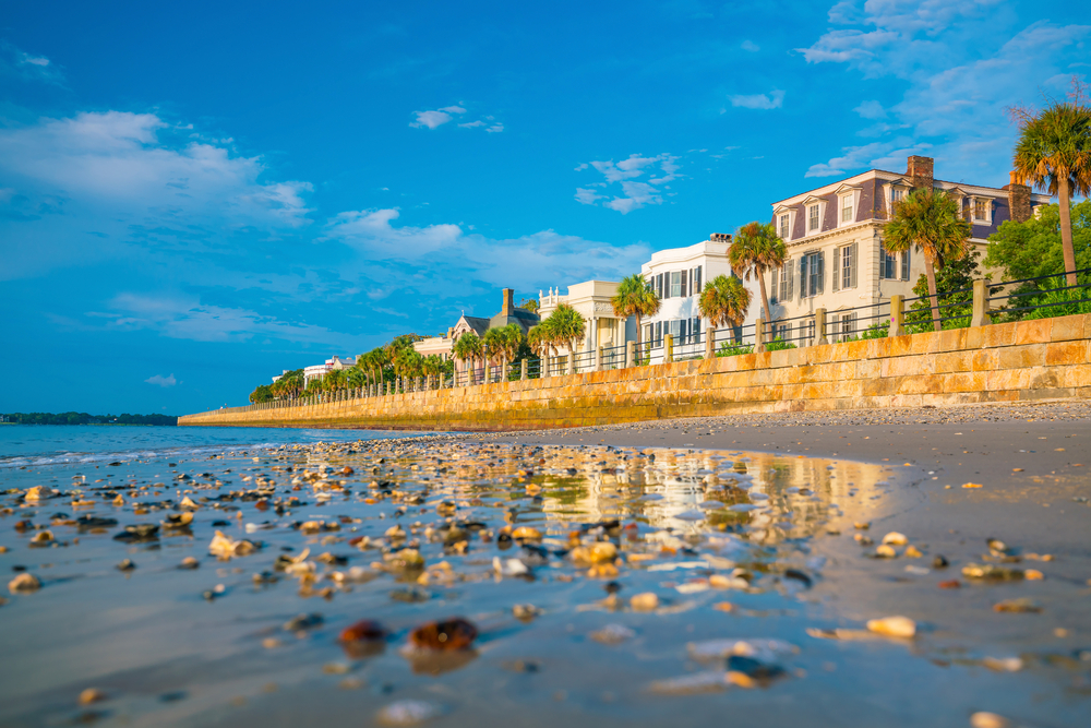 At one of the beach towns in South Carolina, shells litter the beach after high tide, and the buildings behind the shore are highlighted during the golden hour of susnet.