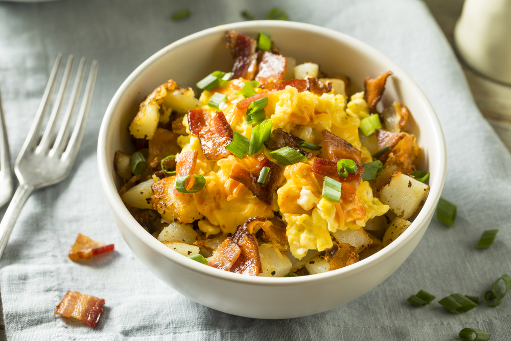 A breakfast bowl filled with eggs, bacon, potatoes and more sits on a nice napkin: this is a common cafe breakfast in New Orleans for those looking to be a bit healthier. 