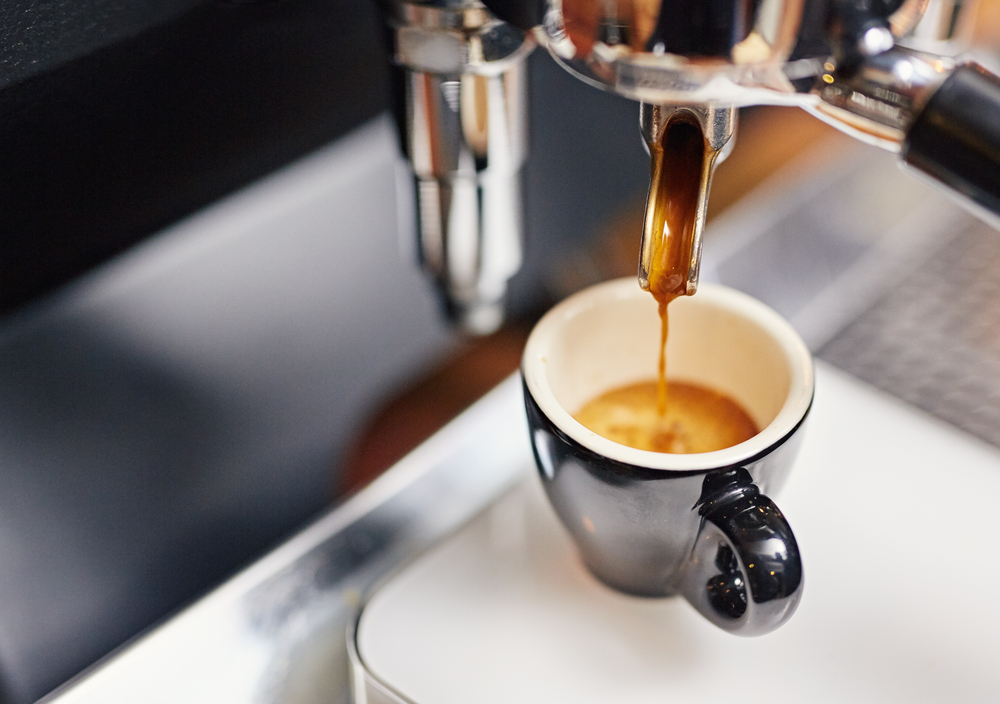 An espresso machine fills a small cup at a bar in NOLA, preparing for the early rush of breakfast in New Orleans.