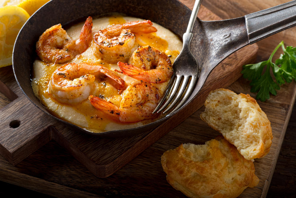 Shrimp and grits are served in a hot skillet with a fork and biscuits: this is one of the most prefect meals for brunch and breakfast in New Orleans.