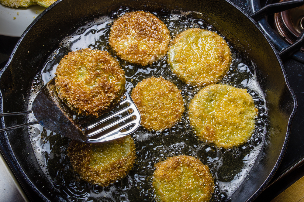 Fried green tomatos are being fried in a pan filled with oil, getting ready for breakfast in New Orleans.