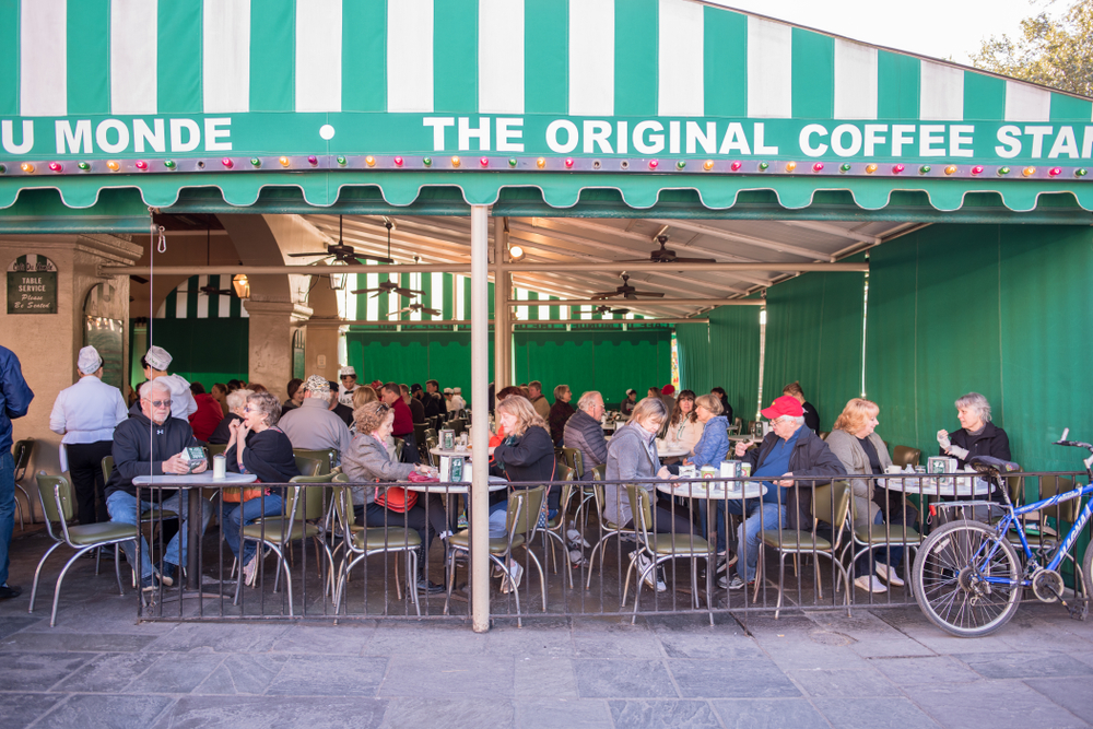 Locals and tourists gather outside on a patio on the french quarter, enjoying breakfast in New Orleans.