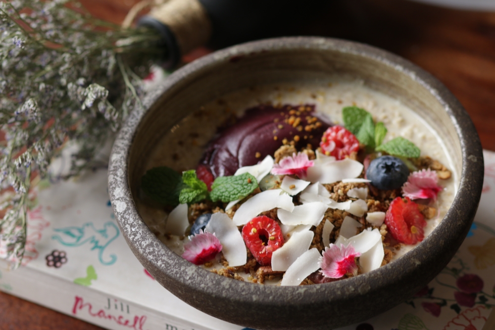 A chai seed pudding bowl is presented with lots of fresh fruit and coconut on tops: this is a healthy option for breakfast in New Orleans.