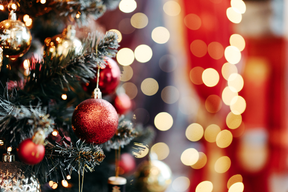 christmas ornaments on tree and lights in the background