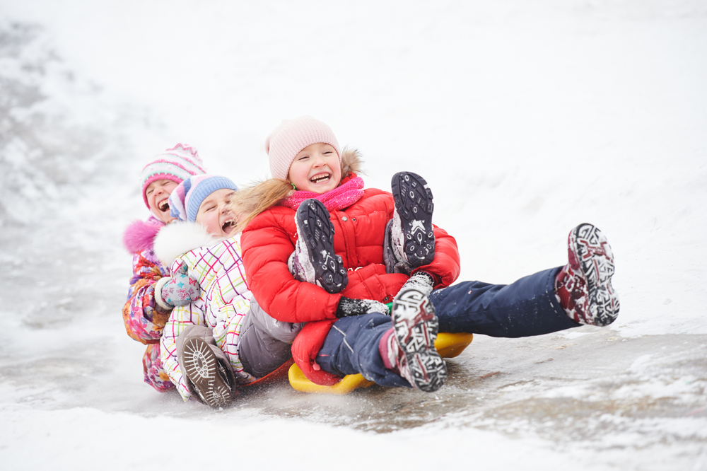 Kids on a sled going ice tubing outside. 