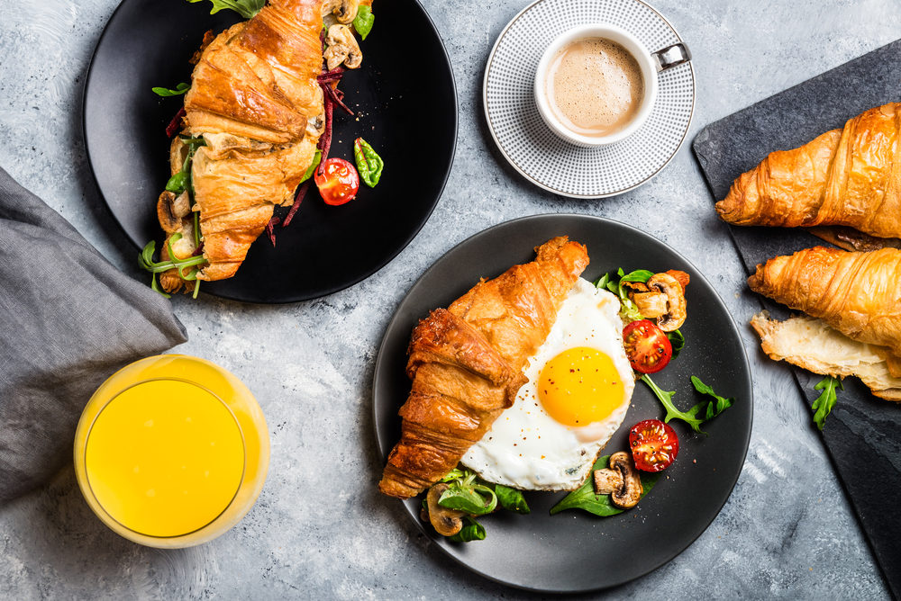 an amazing set of brunch dishes croissants with eggs and coffee and juice