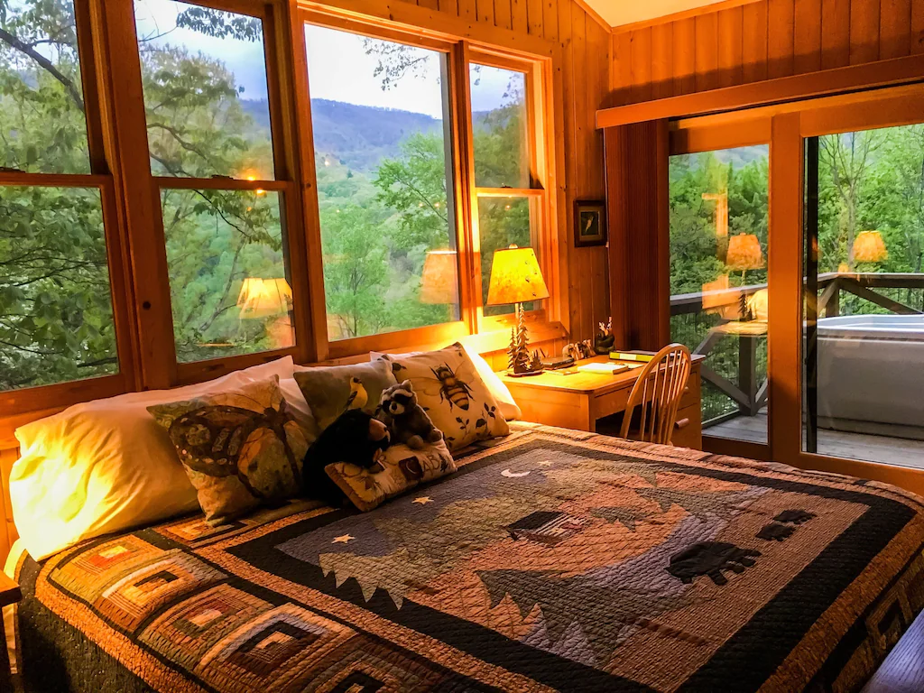 bed in cabin overlooking mountains with hot tub on deck