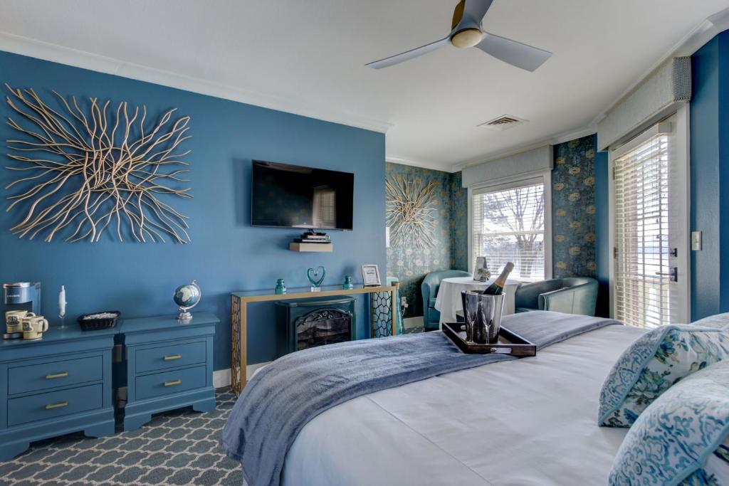 A beautiful hotle toom decorated in blue with a bottle of champagne on the bed. 