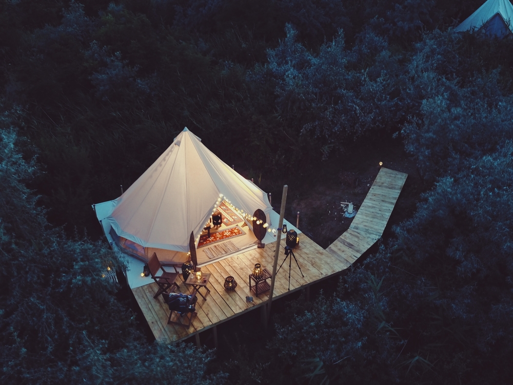 Photo of a glamping set up along the water in the woods. 
