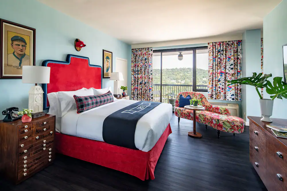 Stylish Hotel bedroom with a large red bed and floral chaise lounge. 
