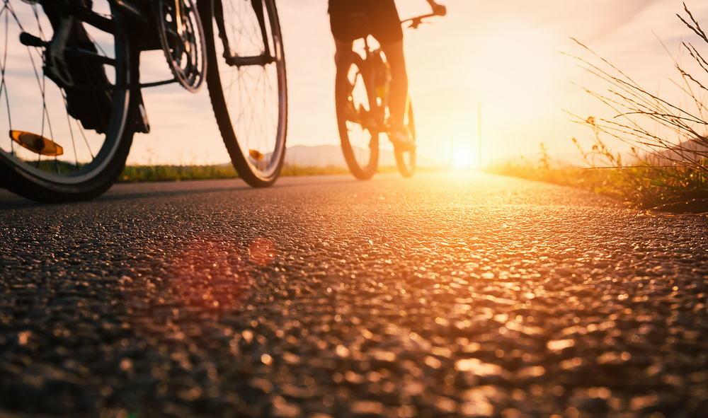 Bike wheels close up image on asphalt sunset road