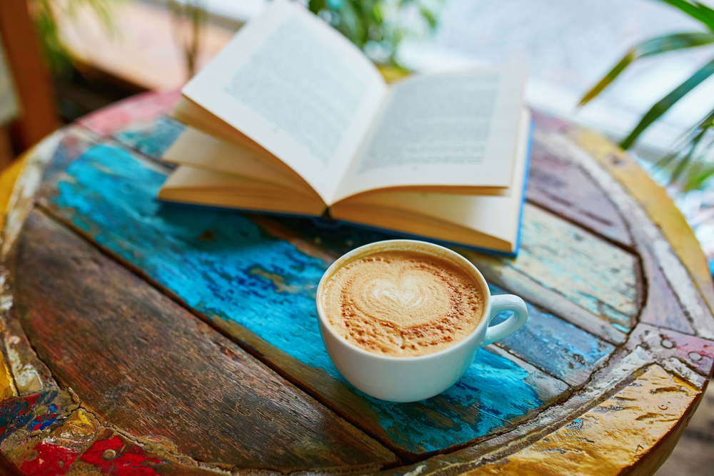 Cup of fresh coffee and book on a wooden table