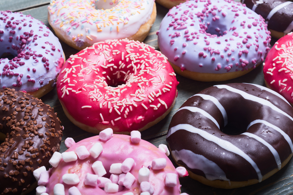 assorted donuts with chocolate frosted, pink glazed and sprinkles donuts.