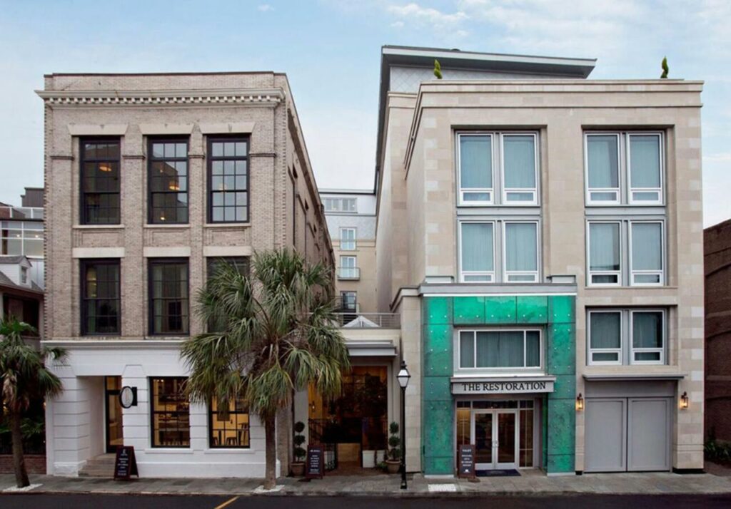an exterior shot of a concrete brick building with rustic metal turquoise trimming featured on the restoration hotel, one of the best boutique hotels in Charleston, SC