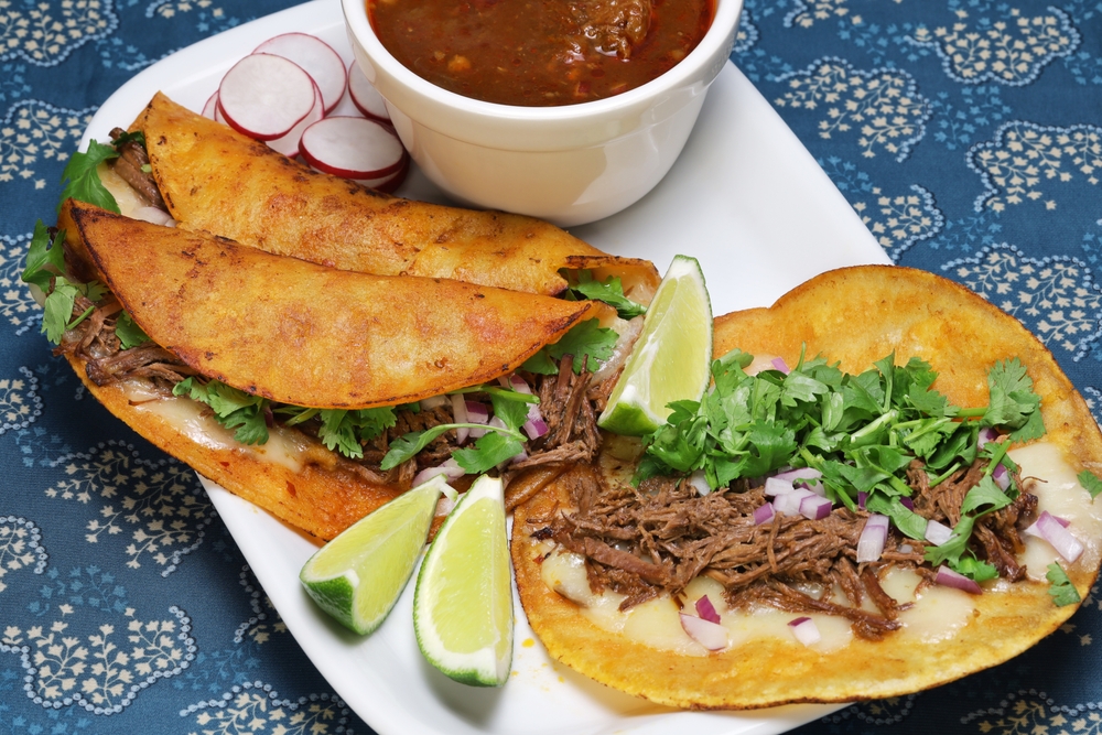 birria tacos on plate with dipping sauce