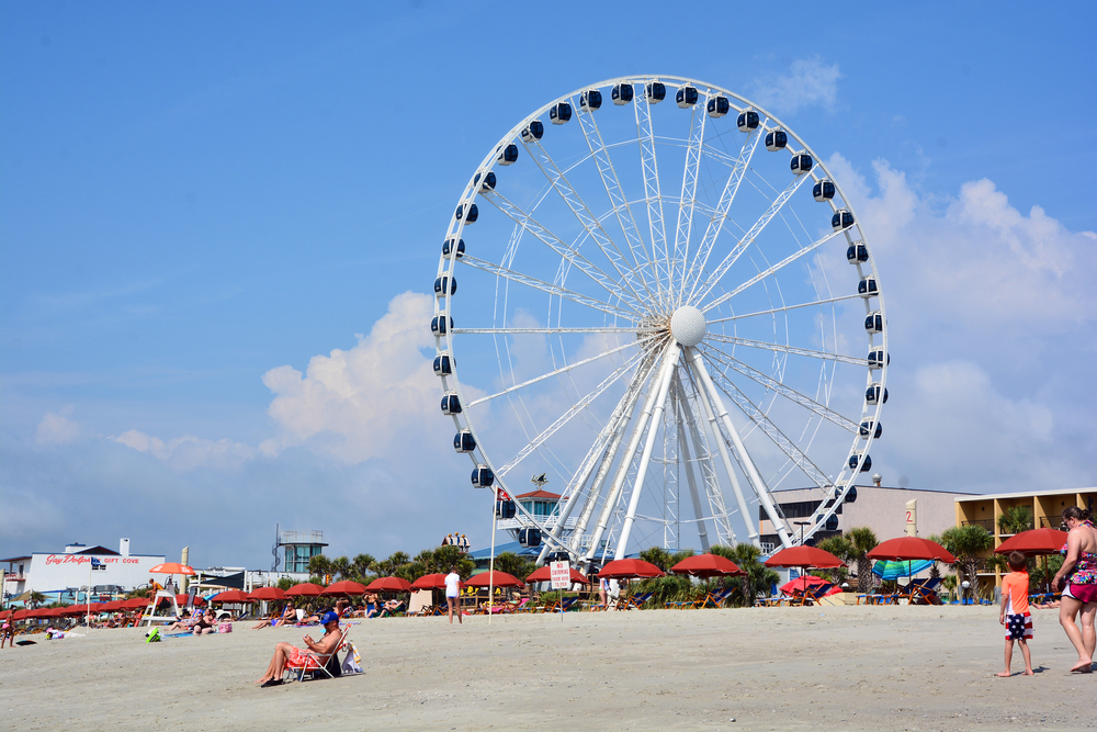 The Skywheel on the beach with umberllesa infront of it. One of the best things to do at myrtle beach 