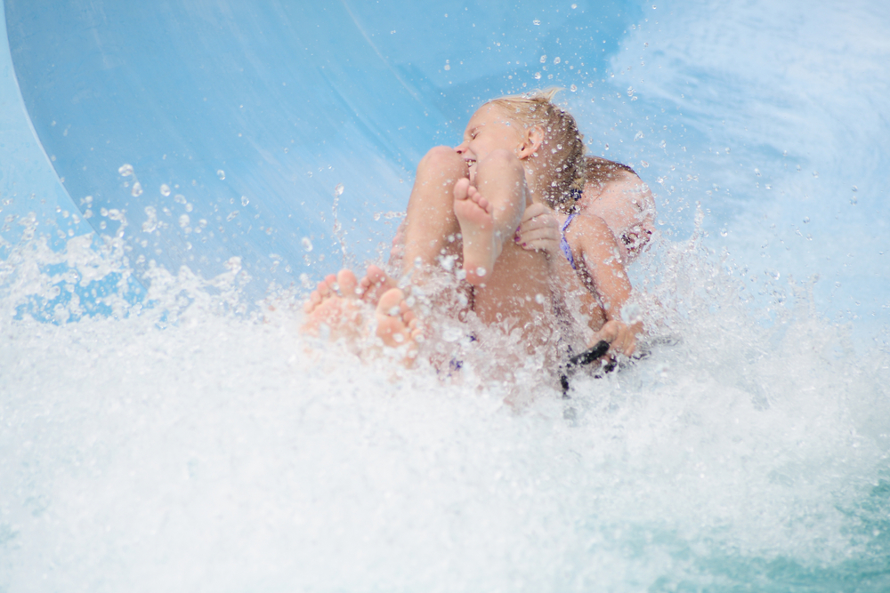 Two children coming down a water slide water all around them. One of the  best things to do is Myrtle Beach 