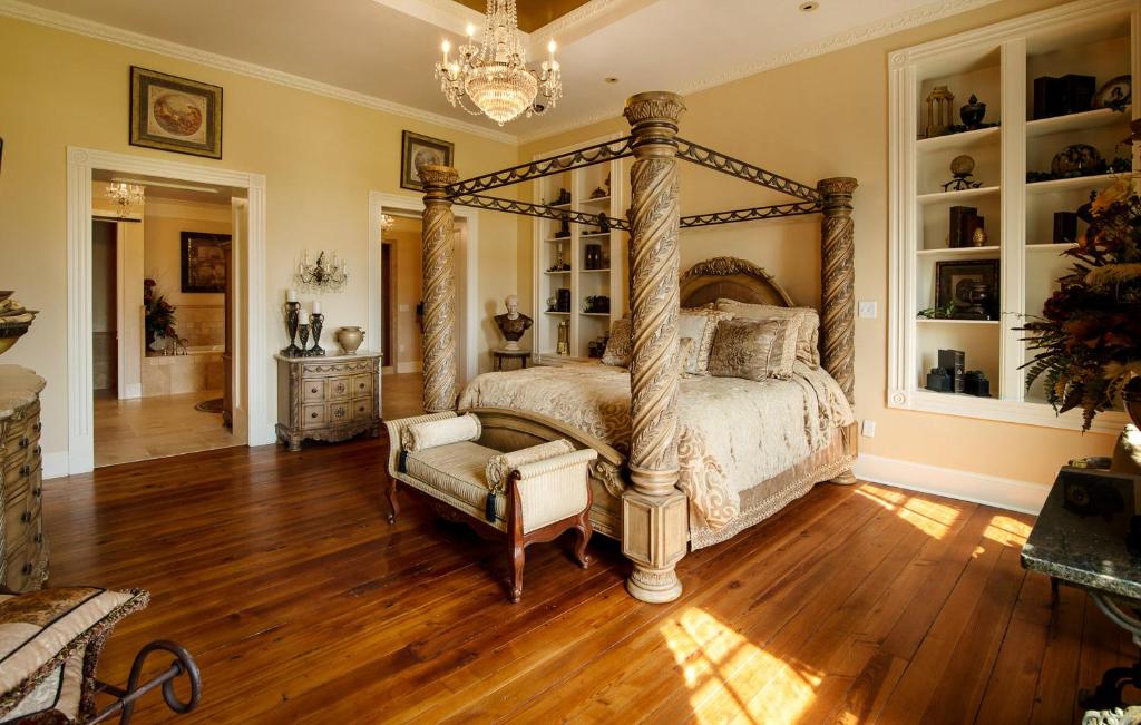 A four poster bed in the middle of a grand room. It has a french chateau feel about it. 
