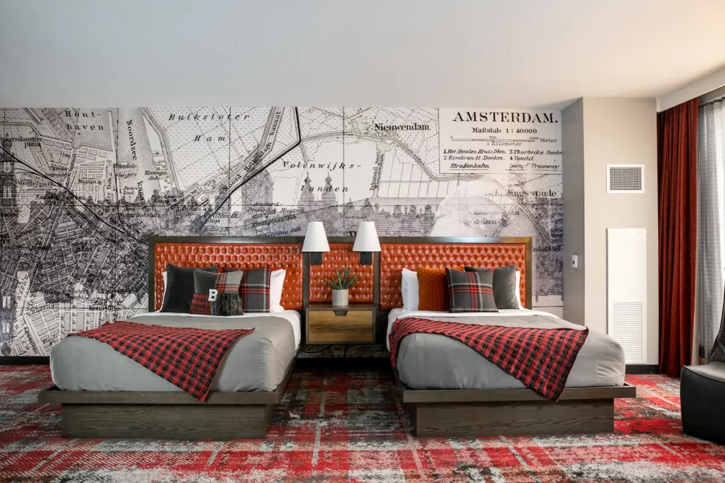 A hotel bedroom with two large beds and a map in the wall. The beds have a large orange headboard. This is one of the best boutique hotels in Nashville. 