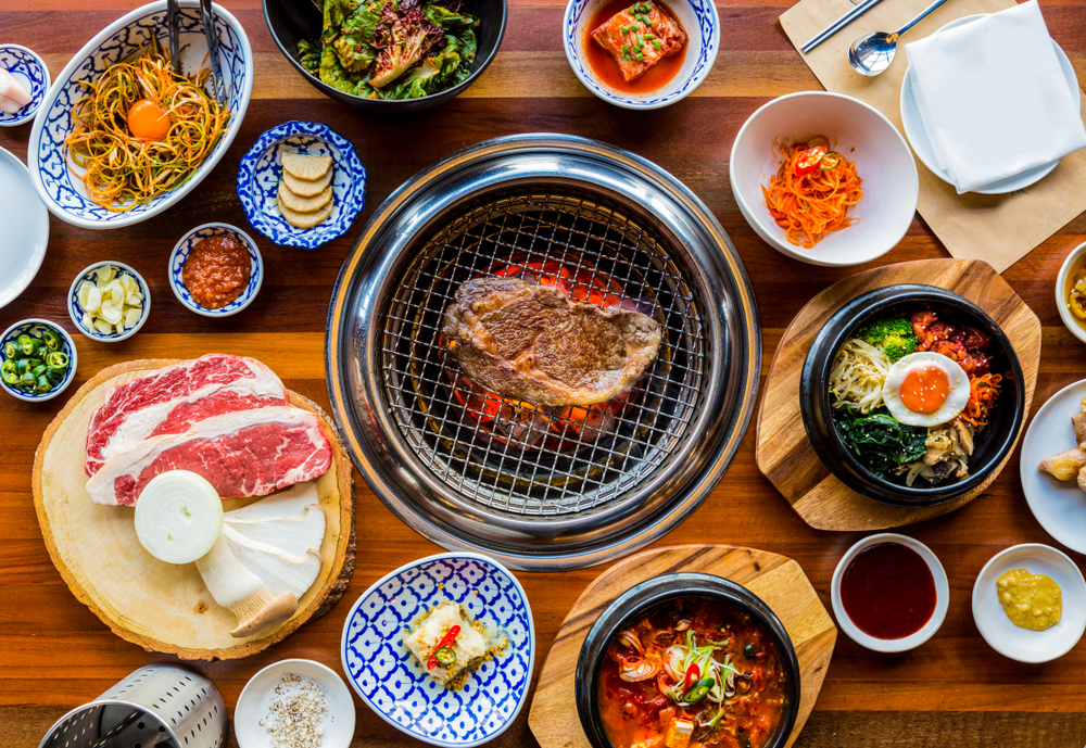 a variety of dishes on table filled with meats, noodles, fish cooked on grill in middle of table at one of the best restaurants in Charlotte