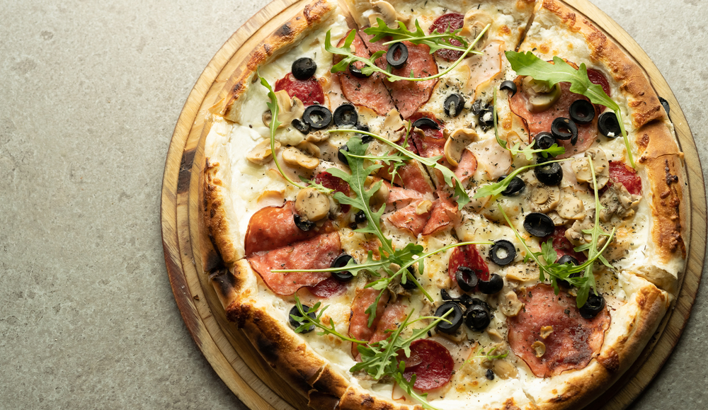 a wood fired pizza with Salami, olives, mushrooms and arugual