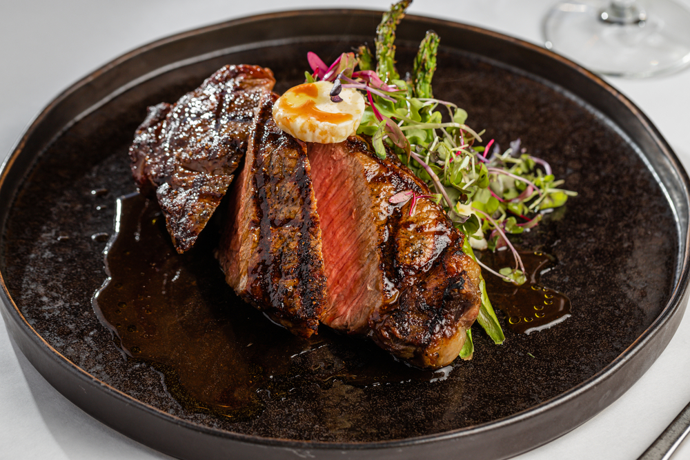 a sliced flank steak with micro greens and grilled veggies