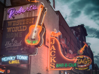 The neon sign of Robert's Western World and Jacks Bar-b-Que lit up as the sky starts to get dark. It's a must-see honky-tonk bar during a weekend in Nashville.