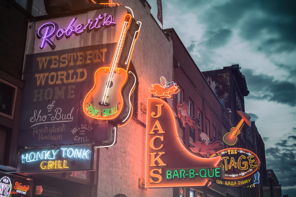 The neon sign of Robert's Western World and Jacks Bar-b-Que lit up as the sky starts to get dark. It's a must-see honky-tonk bar during a weekend in Nashville.