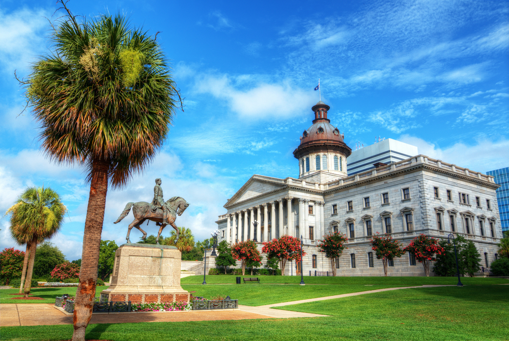 state house with statue in front and palm trees