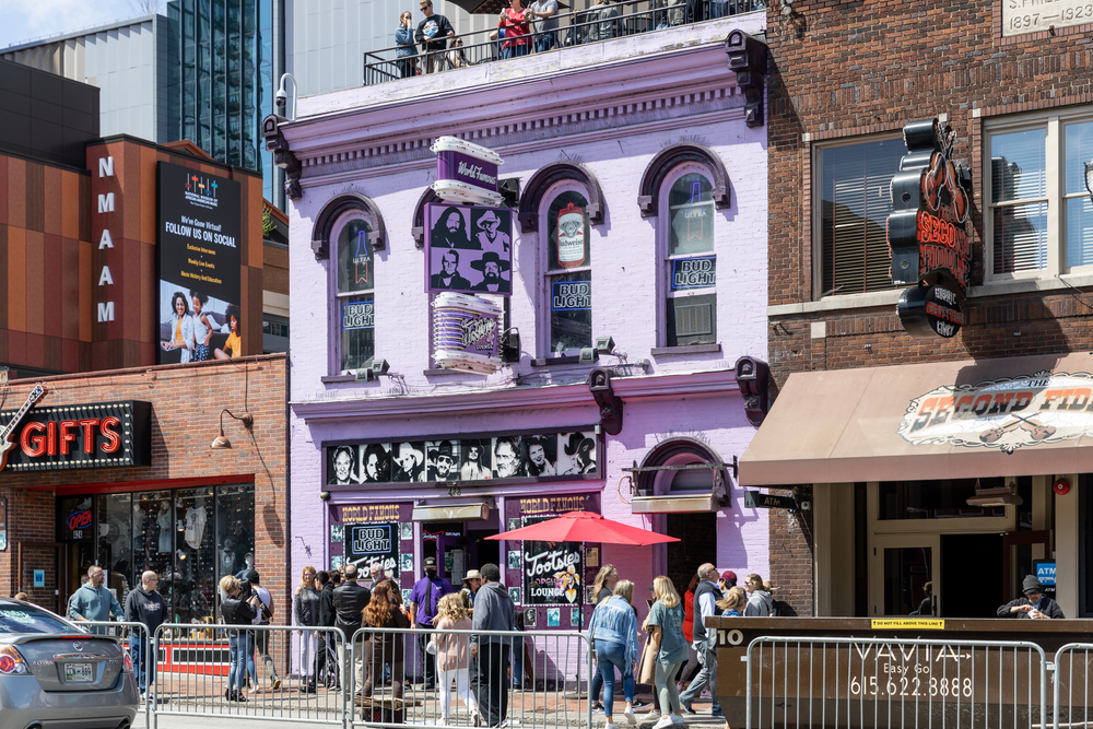 The front of Tootsie's Orchid Lounge, a building in a row of old buildings that is painted light purple. 