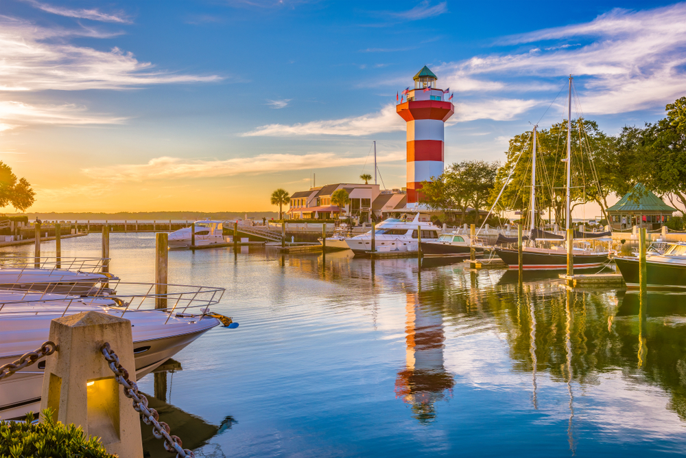 Hilton Head lighthouse at dusk. There are boats in the water 