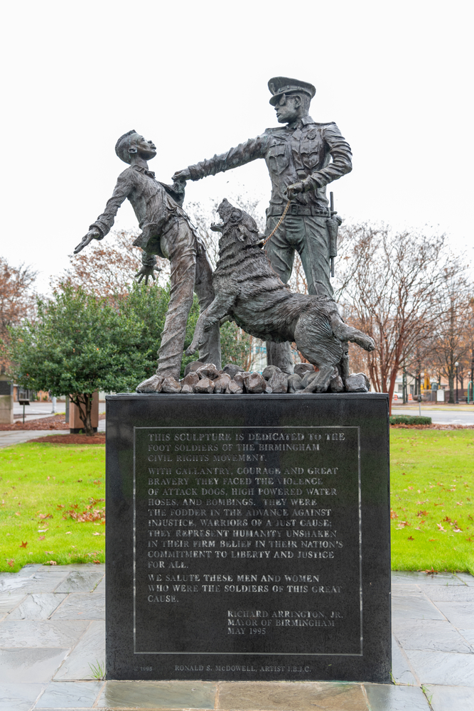 A monument in a park depicting a police officer and dog attacking a man.