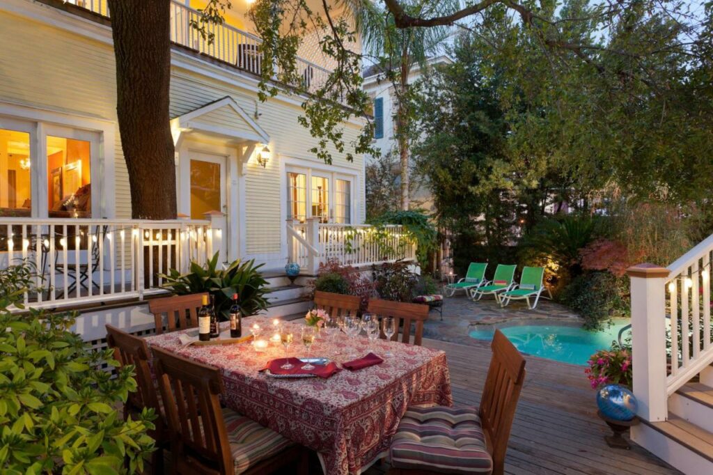 The backyard of the Azalea Inn, one of the best boutique hotels in Savannah. String lights light the back patio, where a table and chairs sit near a sunken hot tub.