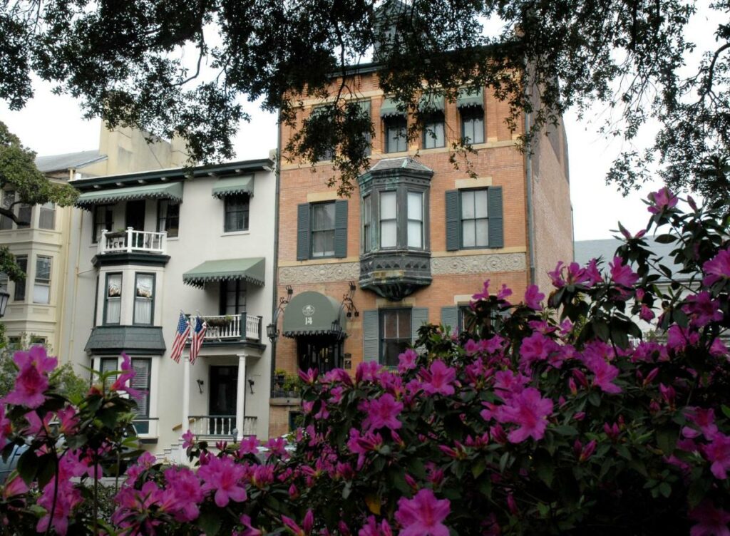 The brick exterior and green shutters of the Foley House, a historic townhouse that is now a boutique hotel in Savannah.