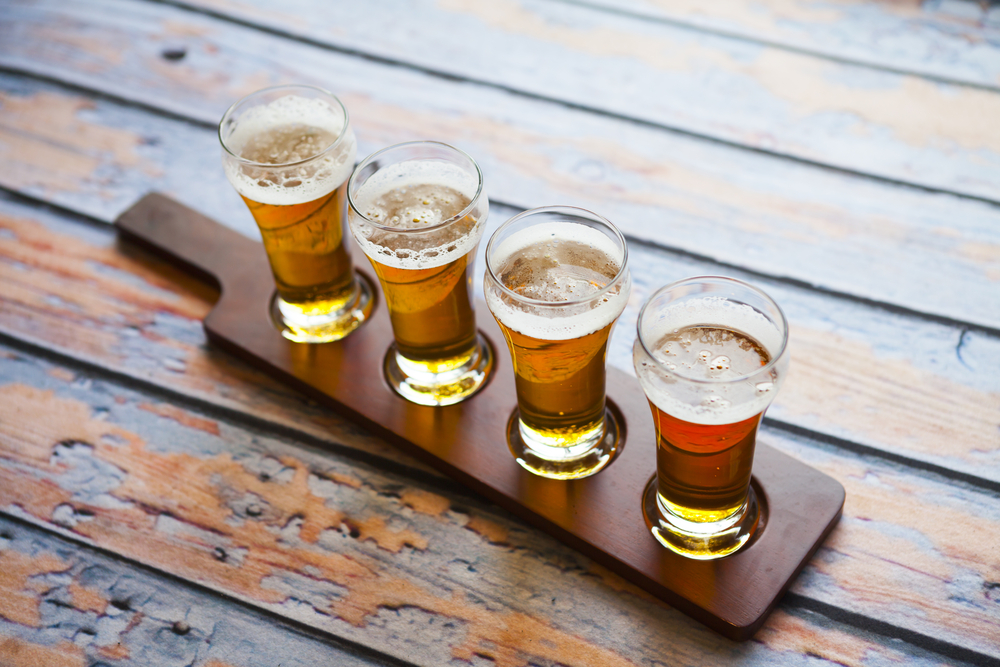 A flight of craft beers on a wooden table.