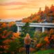 A woman in fall sweater stands looking at Linn Cover Viaduct during fall in North Carolina.